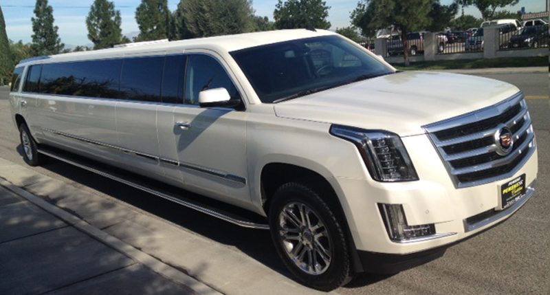 Extended Cadillac Escalade limousine parked near trees